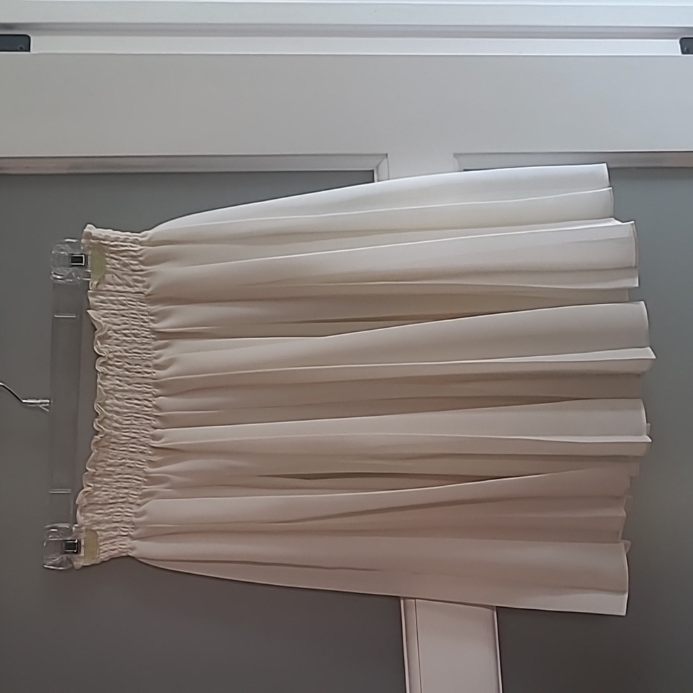A cream colored pleated skirt. Knee length.